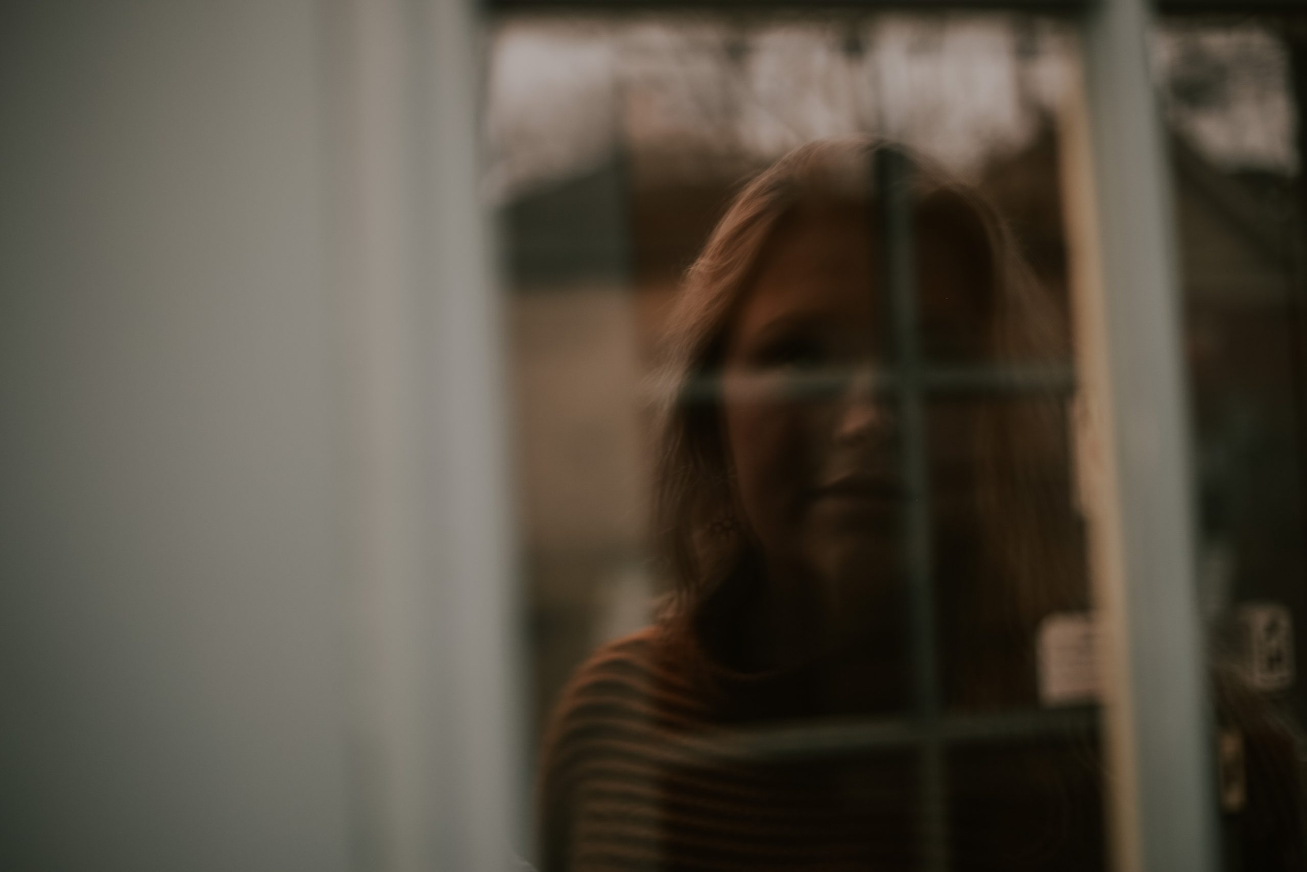 Woman looking through window- Post Traumatic Stress Disorder Symptoms