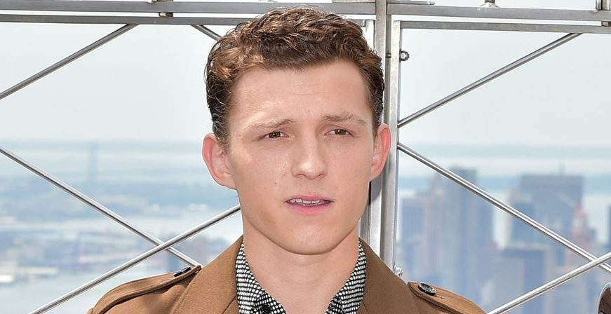 Tom Holland in brown coat and black and white shirt