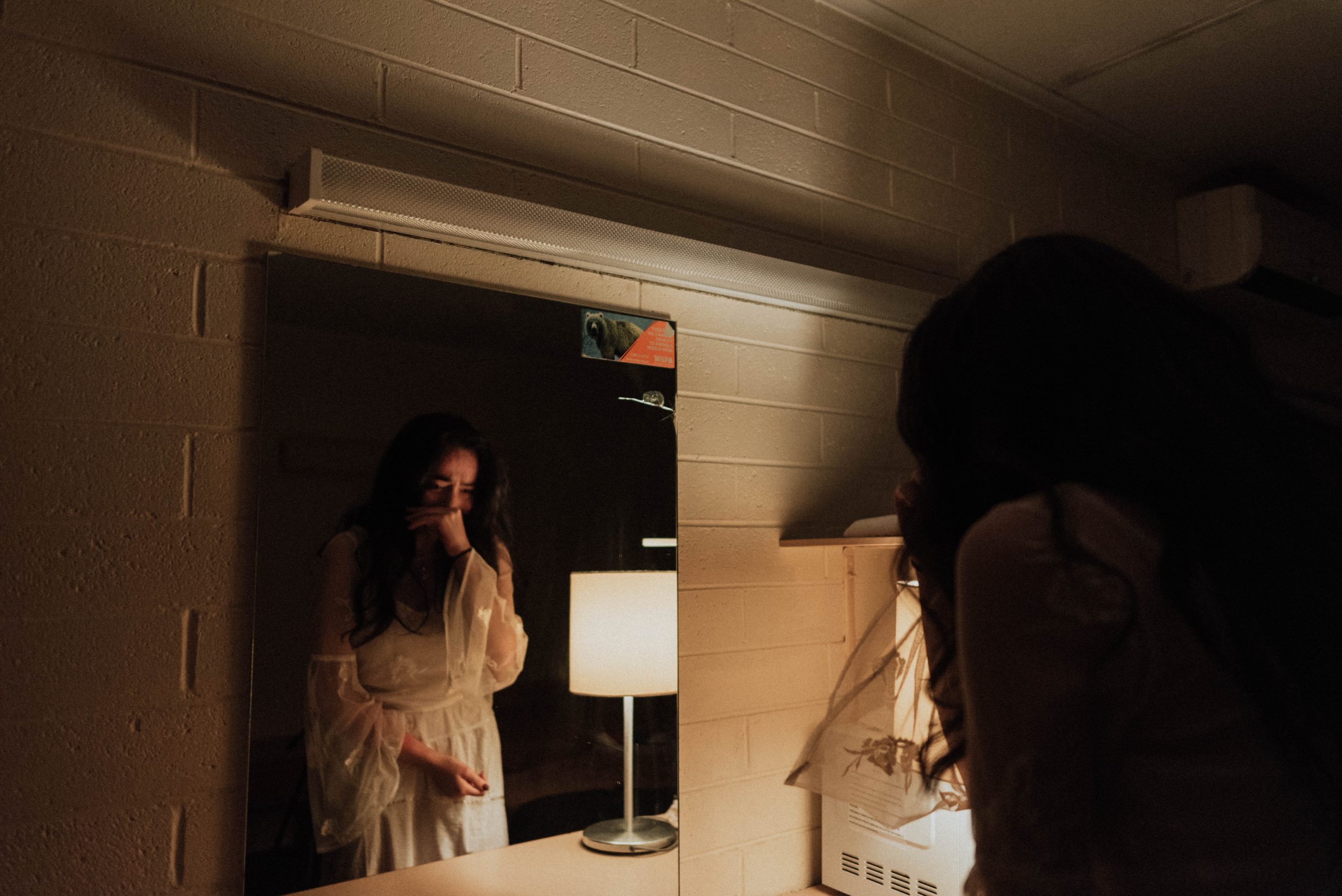 Woman in white dress crying in front of the mirror