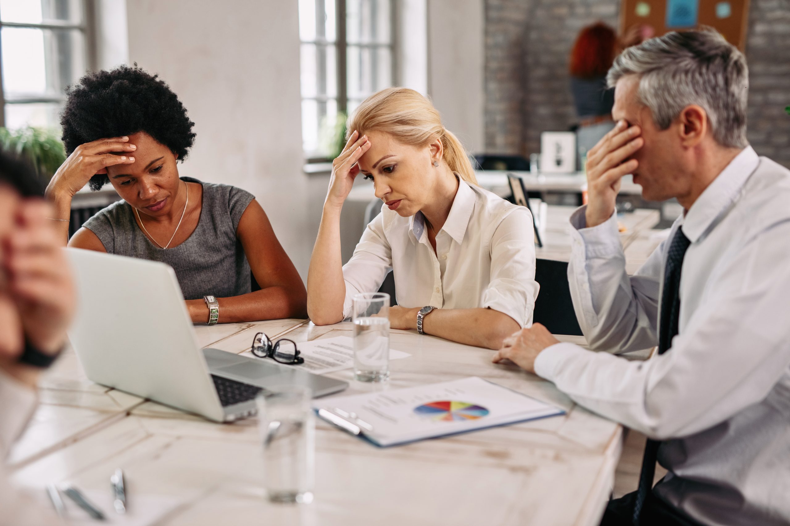 Group of business colleagues having a headache while working on laptop.