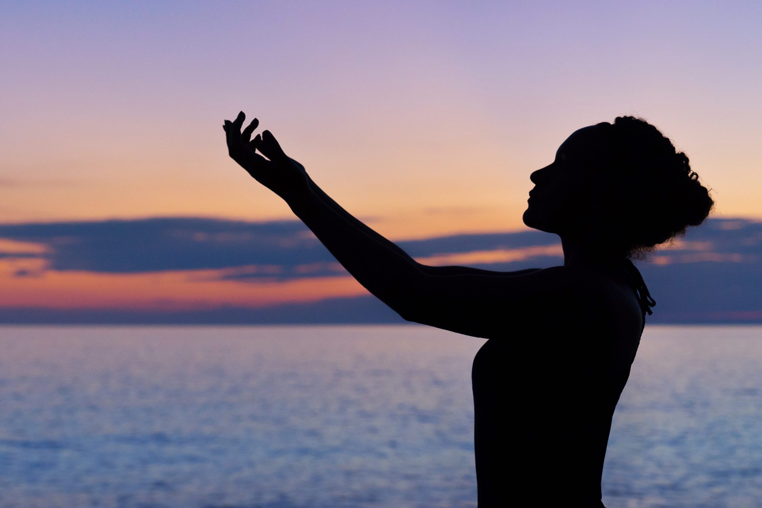 Silhouette of lady raising a hand in air