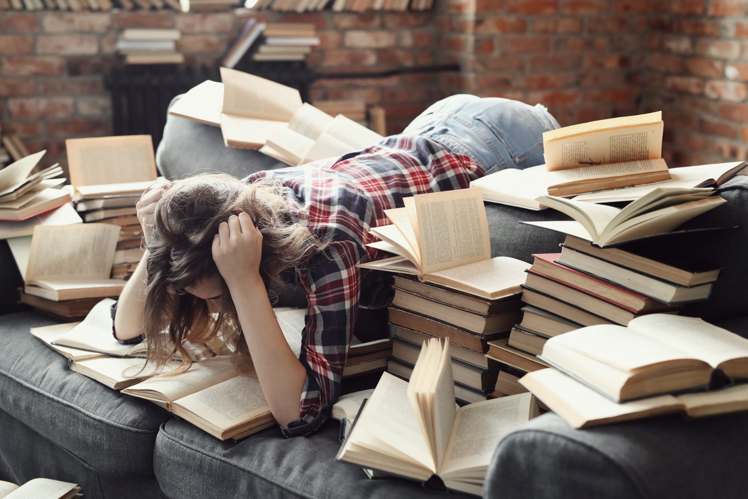 Girl busy reading a book in a cluttered space with books