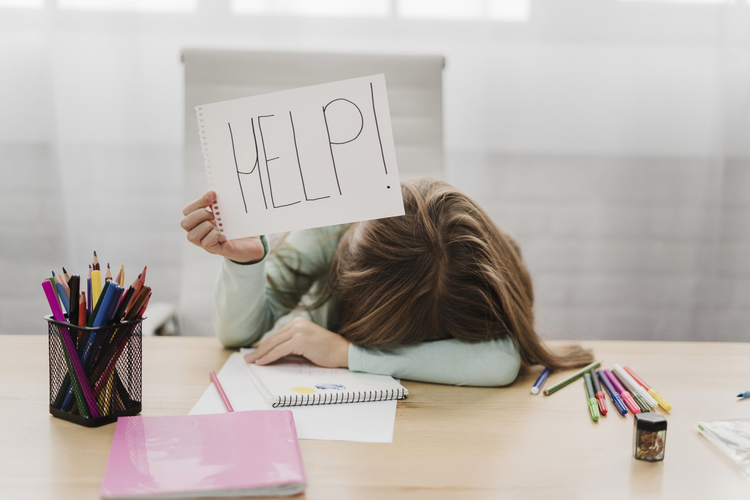 little girl holding a help message on a white paper