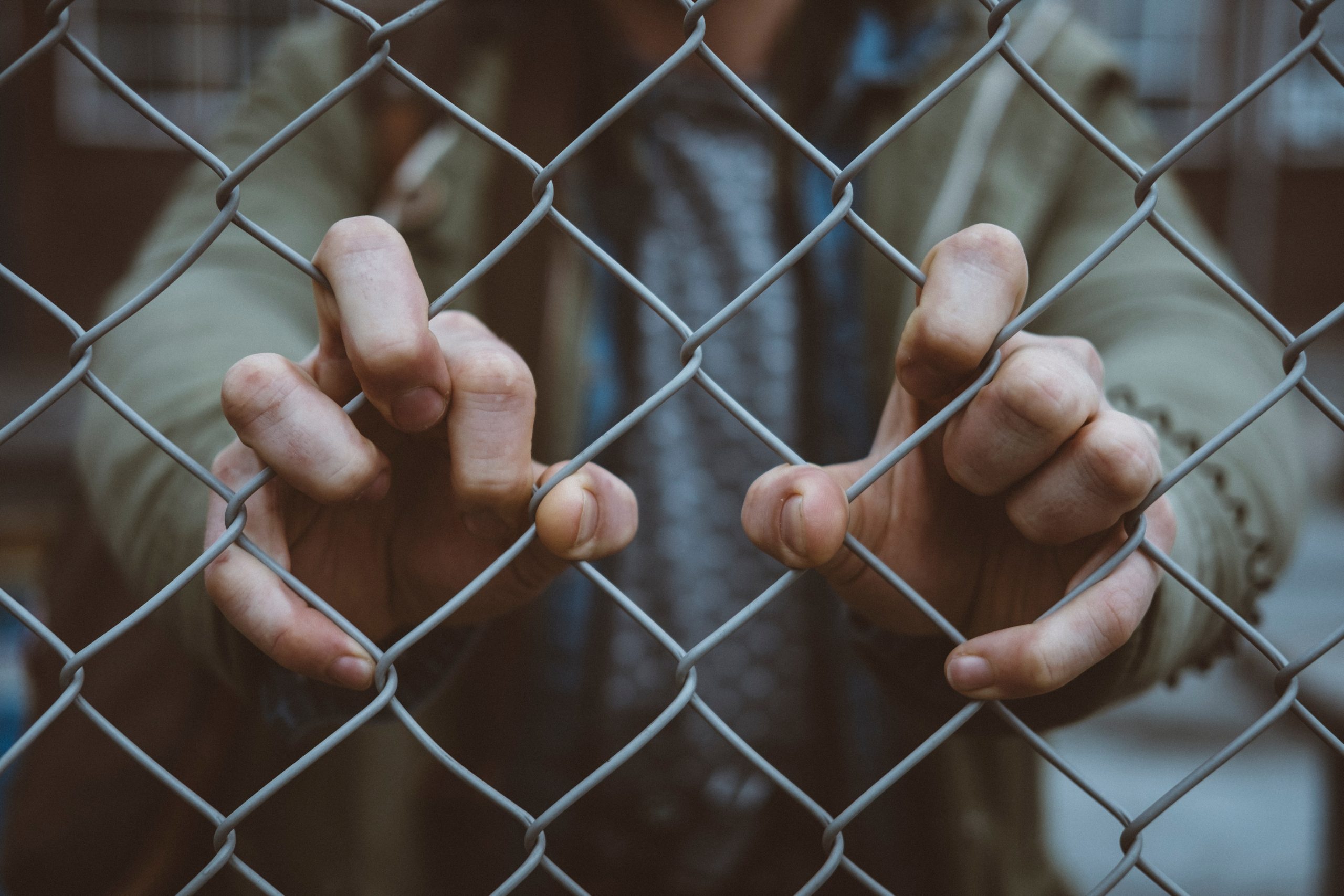 Man holding metal net fence with his hands- Mental Health Stigma