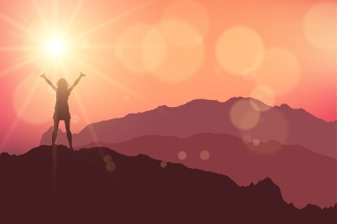 a female stood on top of a mountain against a sunset sky as a symbol of positive affirmation
